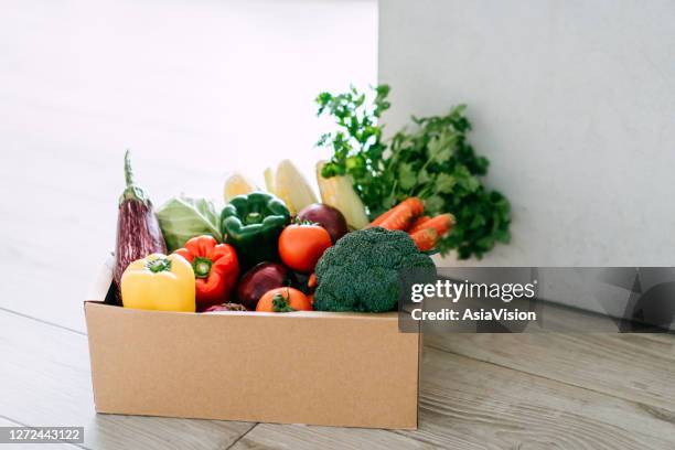 home delivery of a box full of colourful and fresh organic groceries ordered online delivered at the door step - food box stock pictures, royalty-free photos & images