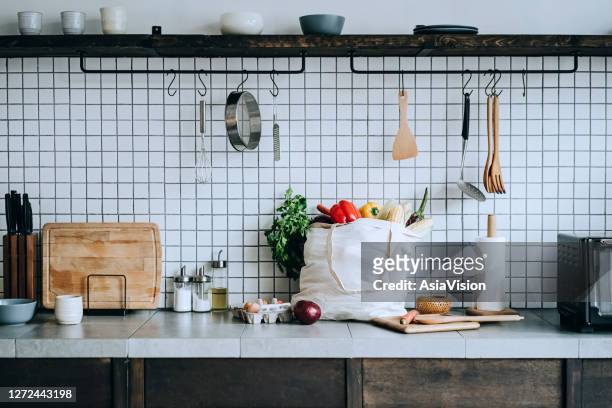 a reusable bag full of colourful and fresh organic vegetables and groceries on the kitchen counter. zero waste shopping and sustainable lifestyle concept - food staple stock pictures, royalty-free photos & images