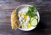Traditional greek yogurt tzatziki sauce with cucumbers and herbs on wooden background