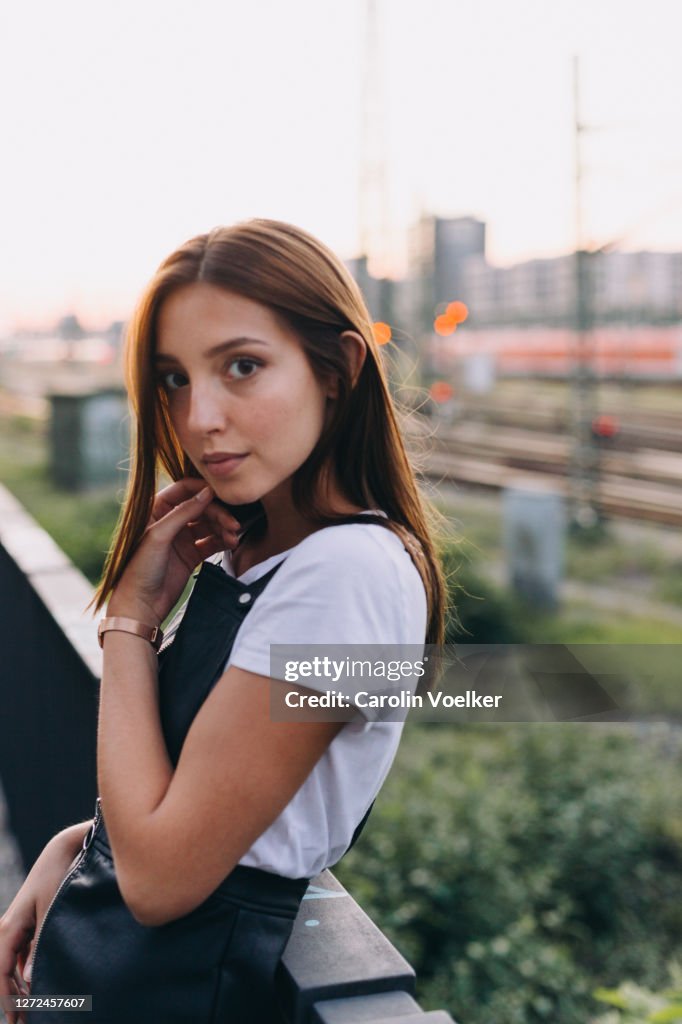 Portrait of young latina woman 20-24 years old looking at the camera over shoulder wearing a white tshirt and a mini dress