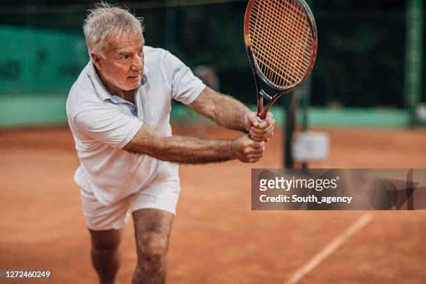 senior man playing tennis - senior tennis stock pictures, royalty-free photos & images