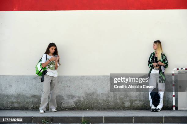 Two young student girls without protective masks but with the right distance outside a school just before entering the classroom on Liceo Da Vinci of...