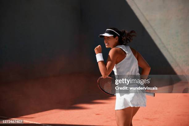 female tennis player celebrating victory during match on clay court - tennis game stock pictures, royalty-free photos & images