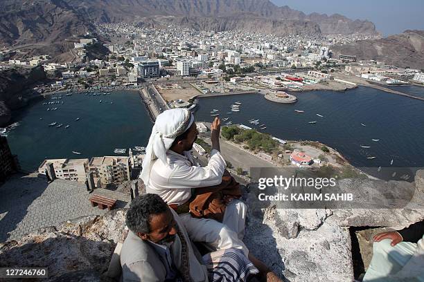 Yemeni men sit on a mountain top overlooking Aden city centre in southern Yemen on November 22, 2010 as the restive country prepares to host the Gulf...