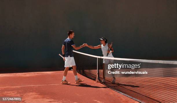 two tennis players fist bumping after match on clay court - tennis club stock pictures, royalty-free photos & images