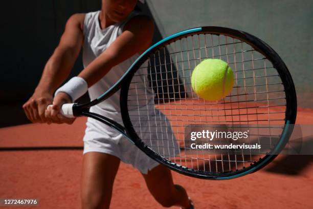 nahaufnahme frau schlagen ball während tennis-match auf sandplatz - racquet stock-fotos und bilder