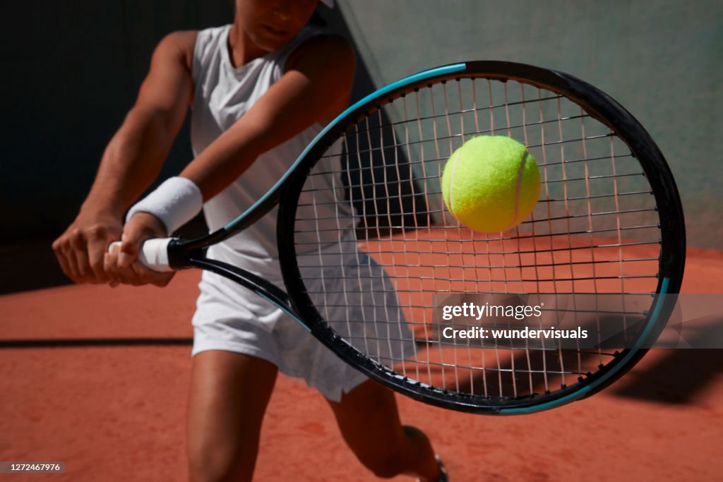 Close-up woman hitting ball during tennis match on clay court