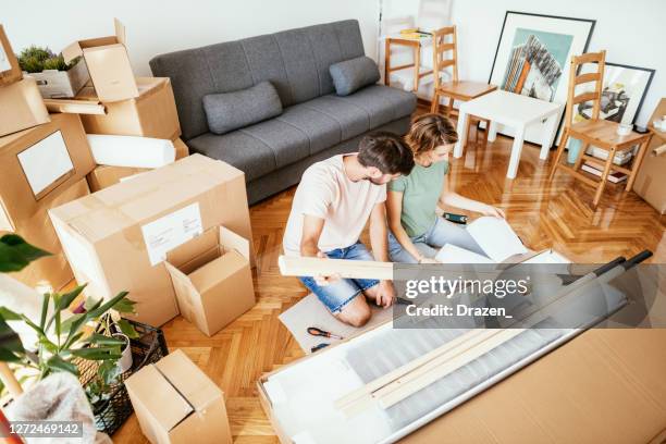 coppia che si muove in un nuovo appartamento e assembla mobili, unboxing mobili flat pack - furniture maker foto e immagini stock