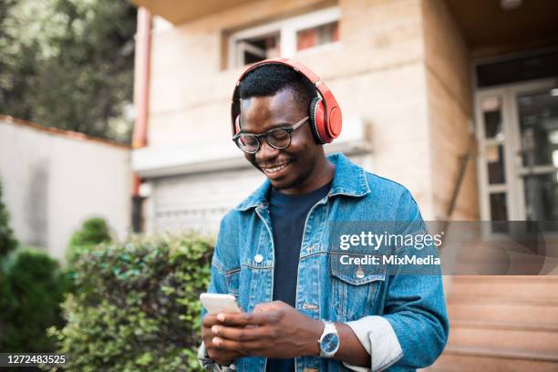 african-american young man podcasting on his way to the city - podcast headphones stock pictures, royalty-free photos & images