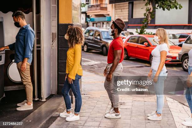 social distancing in line at atm - lining up imagens e fotografias de stock