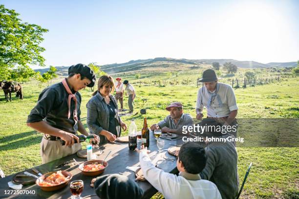 familia gaucho argentina disfrutando de comida al aire libre al mediodía - argentino fotografías e imágenes de stock