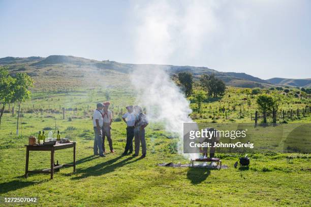 gauchos sprechen, während grillmeister fleisch kontrolliert - pampa argentine stock-fotos und bilder