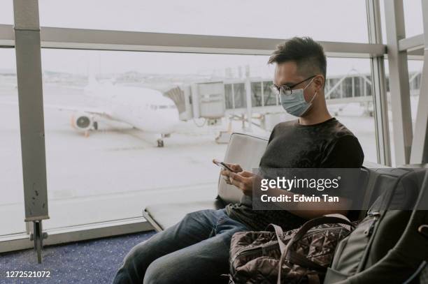 asian chinese traveller in airport observing social distancing with face mask - kuala lumpur airport stock pictures, royalty-free photos & images