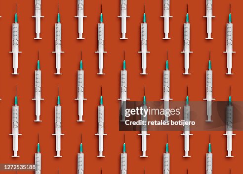 Medical syringes organized in a pattern on orange background Medical syringes organized in a pattern on orange background