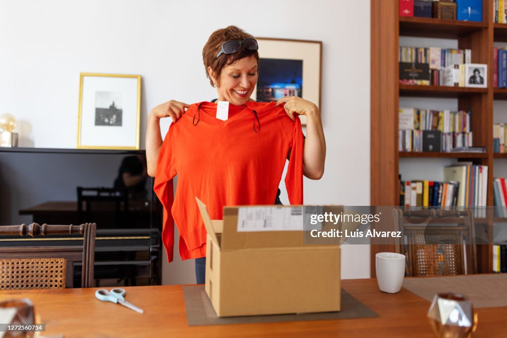 Woman looking at online purchased clothing at home