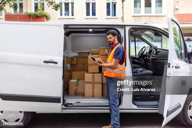 delivery man using digital tablet by van - mailman stock-fotos und bilder