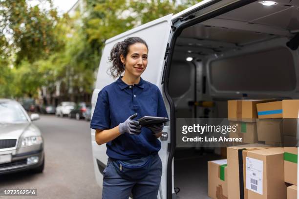 female courier worker standing by delivery van - blue polo shirt fotografías e imágenes de stock