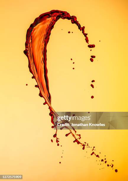 red wine splatter on yellow background - wine splash stock pictures, royalty-free photos & images