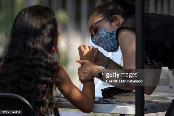 Woman administers a swab test to a young girl at a Covid Test site in South London on September 15, 2020 in Greater London, England. The site saw a...