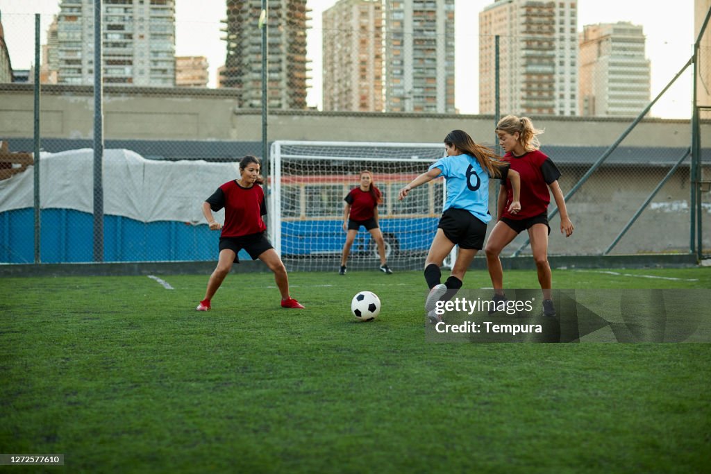 Vrouwelijke voetballer die een tegenstanderverdediger dribbelt.