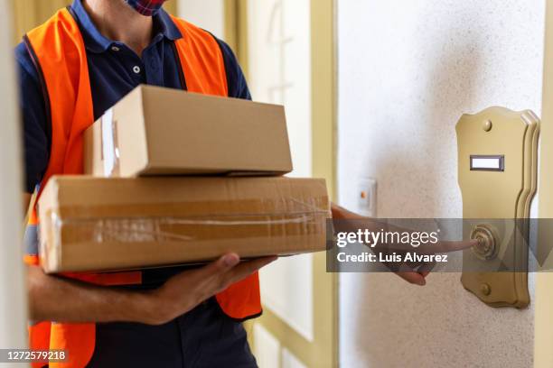 postal worker doing a home delivery of parcel - doorbell stock-fotos und bilder