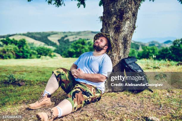 plump male hiker taking a nap while leaning on tree in forest - macedonia country stock pictures, royalty-free photos & images