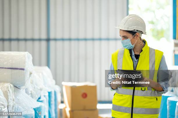 female warehouse worker check, counting raw material and confirm by warehouse management software on tablet. - occupational safety and health stock-fotos und bilder