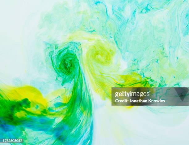 yellow and green dye mixing in water - adattabile foto e immagini stock