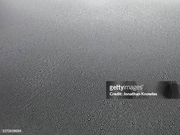 water droplets on gray surface - raindrop stock pictures, royalty-free photos & images
