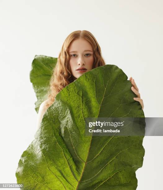 beautiful young redhead woman with big leaves - woman green hair stock pictures, royalty-free photos & images