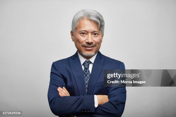 confident mature entrepreneur with arms crossed on white background - business man front foto e immagini stock