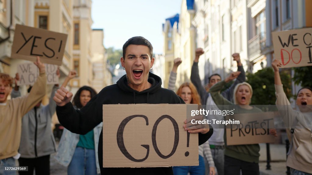Man Aktivist zeigt Go-Plakat mit multiraciaal Menschen Protestaktivisten im Hintergrund