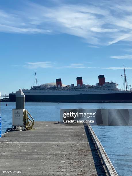giovane donna seduta sul molo con il cane con rms queen mary sullo sfondo - cruise liner foto e immagini stock