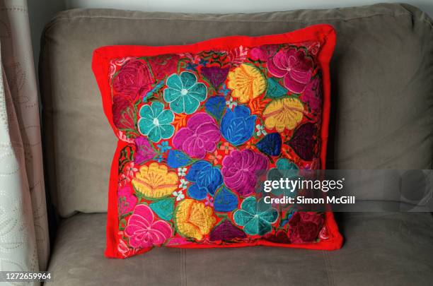 cushion cover embroidered with a traditional mexican floral pattern in bright colours on a grey sofa - cushion imagens e fotografias de stock