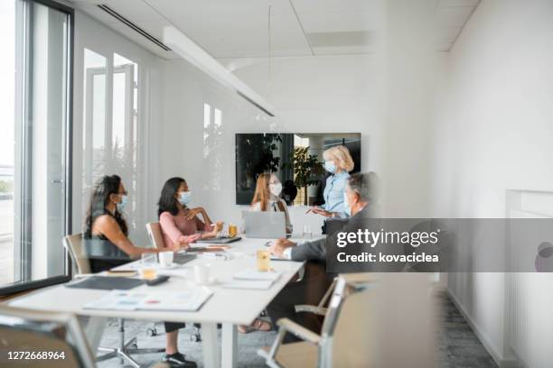 multi ethnic group of people wearing surgical masks during business meeting - coronavirus slovenia stock pictures, royalty-free photos & images