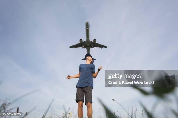 boy jumping and looking at flying airplane - kid looking down stock pictures, royalty-free photos & images