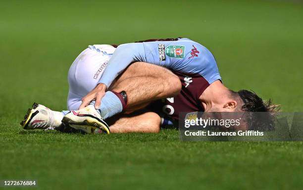 Jack Grealish of Aston Villa holds his leg after a challenge during the Carabao Cup Second Round match between Burton Albion and Aston Villa at...