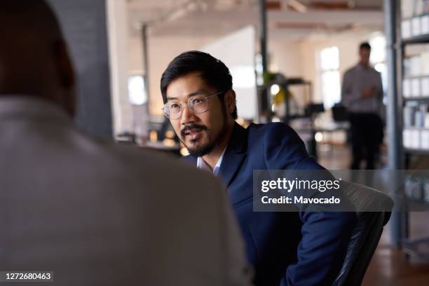 young asian businessman talking with an office colleague - boss over shoulder stock-fotos und bilder