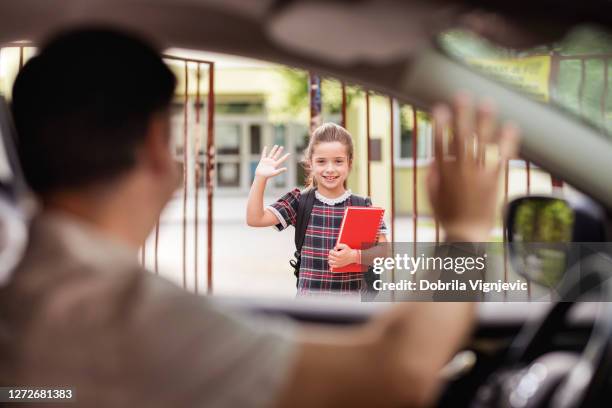 meisje dat zich voor schoolwerf bevindt en haar vader begroet die door in een auto overgaat - waving stockfoto's en -beelden