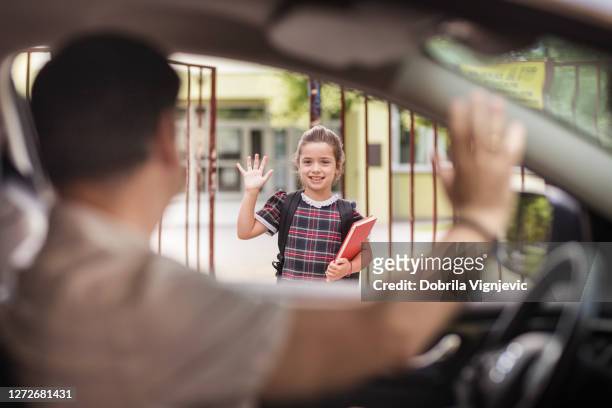 girl standing in front of school yard and greeting her father passing by in a car - car arrival stock pictures, royalty-free photos & images