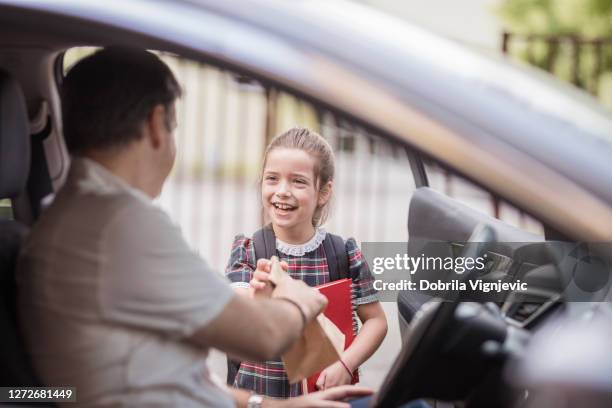 felice ragazza della scuola che riceve il suo pranzo box fro padre - auto box foto e immagini stock