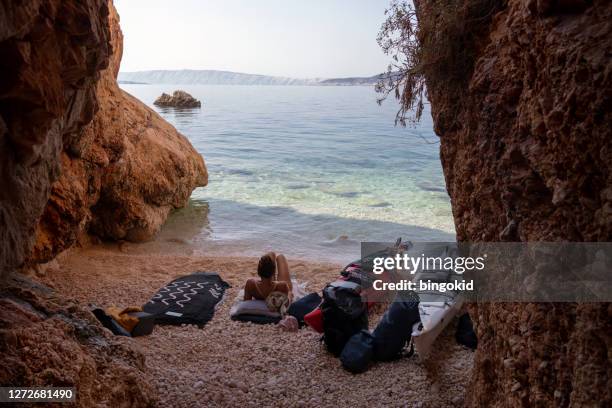 woman sitting on hidden beach among the cliffs - mystery island stock pictures, royalty-free photos & images