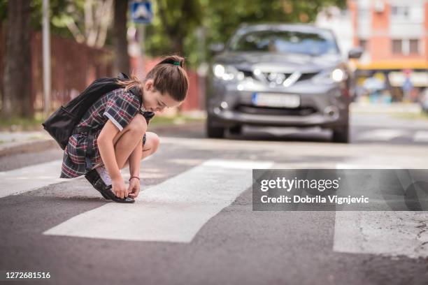 girl fixing her shoeson at the crosswalk - child danger stock pictures, royalty-free photos & images