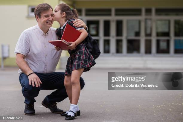 glad flicka holing bok och kysser hennes pappa - schoolgirl bildbanksfoton och bilder