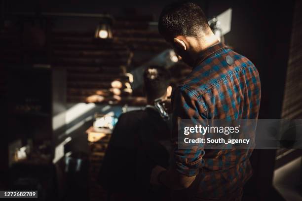 man getting haircut by male hairdresser at barbershop - hair clipper stock pictures, royalty-free photos & images