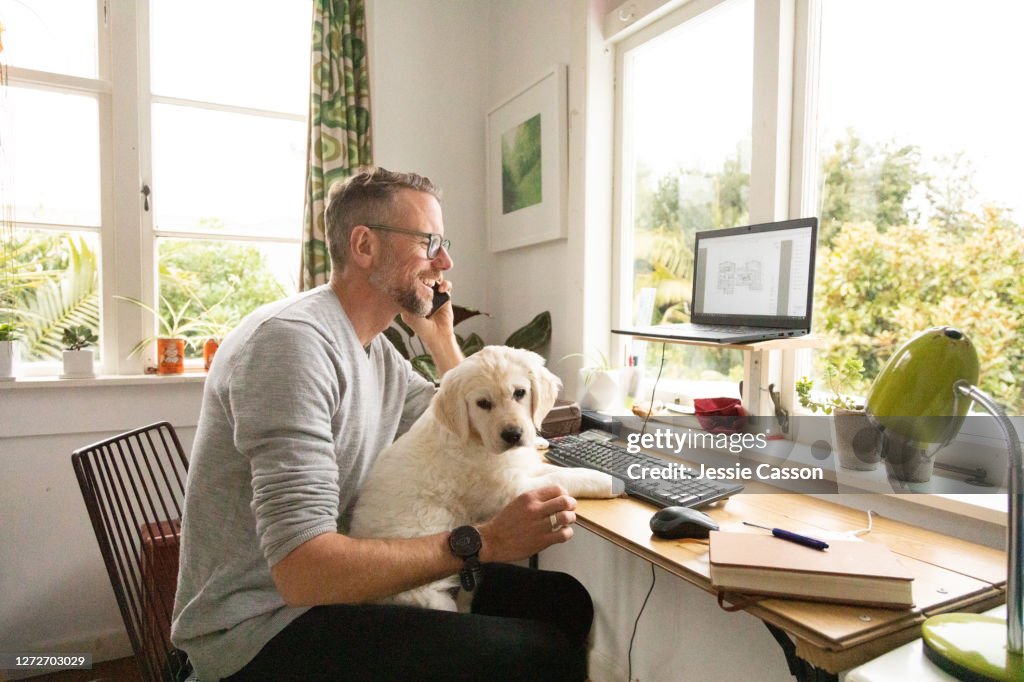 Man working from home with cute puppy on his knee