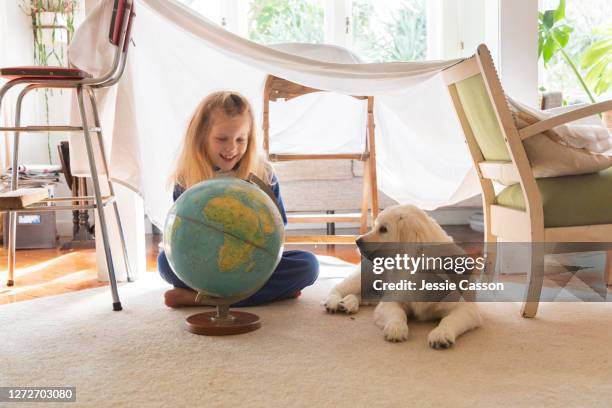 girl and puppy look at globe in homemade house - casa de brinquedo imagens e fotografias de stock