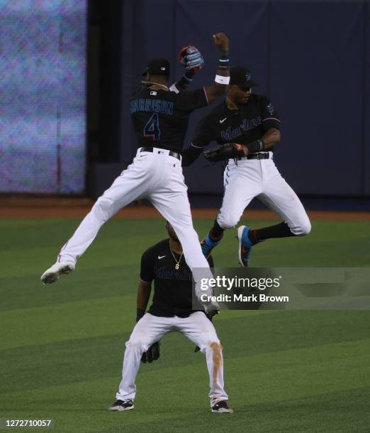 Starling Marte of the Miami Marlins watches as Lewis Brinson and Monte Harrison leap in the air to celebrate winning game two of a double header...