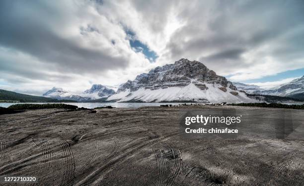 spiaggia sporca vuota con tracce contro le montagne rocciose canadesi - strada in terra battuta foto e immagini stock