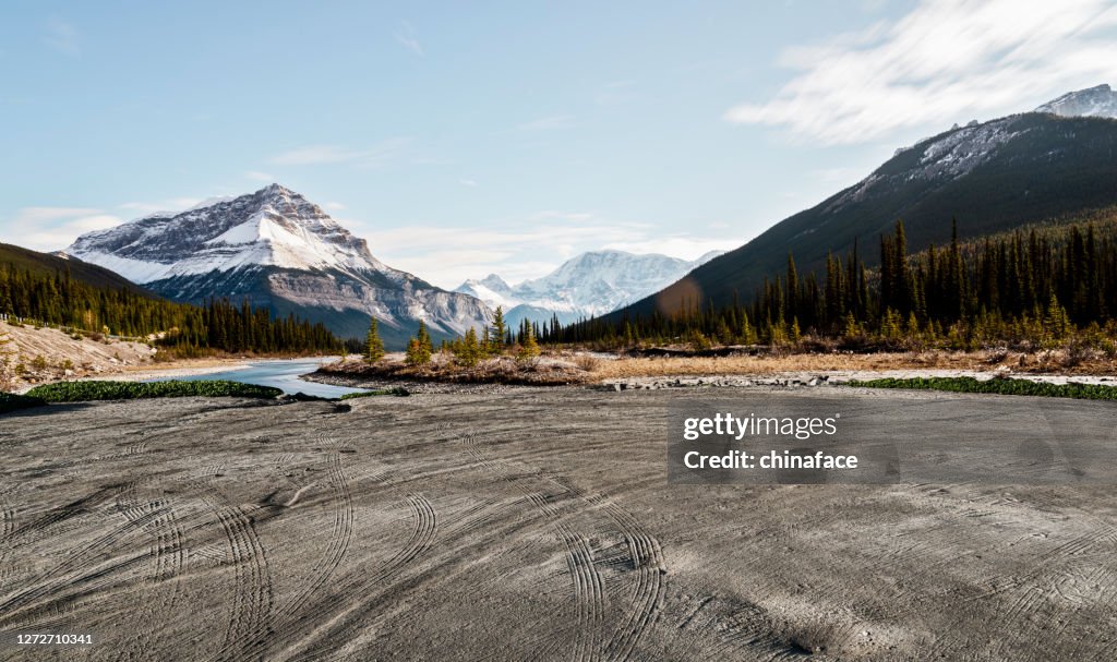 Playa de tierra vacía con rastros contra las Montañas Rocosas Canadienses
